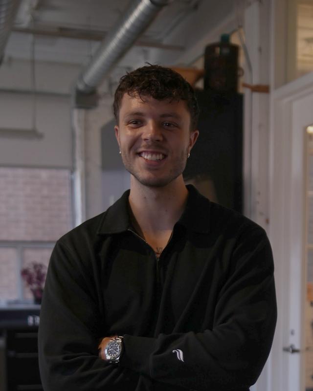 Matt Bender, smiling in the office with his arms folded.